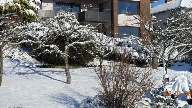 A two-story house with a snow-covered roof and a balcony.