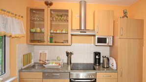 Una cucina compatta con mobili in legno, forno a microonde integrato, forno e lavandino.