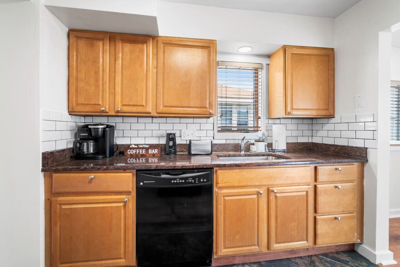 A compact kitchen with wooden cabinets, a coffee maker, a toaster, and a dishwasher.