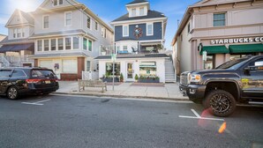 A street view with a two-story building featuring a Starbucks sign, a parked SUV, and a residential building with a balcony.
