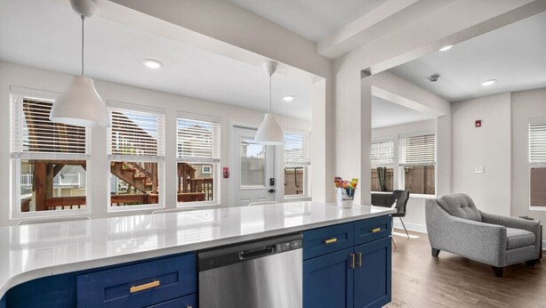 A modern kitchen with a large island, blue cabinets, and pendant lighting.