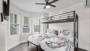 A bedroom with a bunk bed, a ceiling fan, and a window with blinds.
