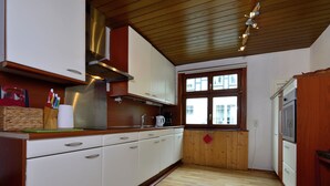 A kitchen with wooden cabinets, a stainless steel range hood, a window with a view, and a refrigerator. - Holiday Home Near Winterberg Ski Slopes (Olsberg)