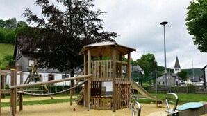 A playground with a wooden climbing structure, slides, and swings. - Holiday Home Near Winterberg Ski Slopes (Olsberg)