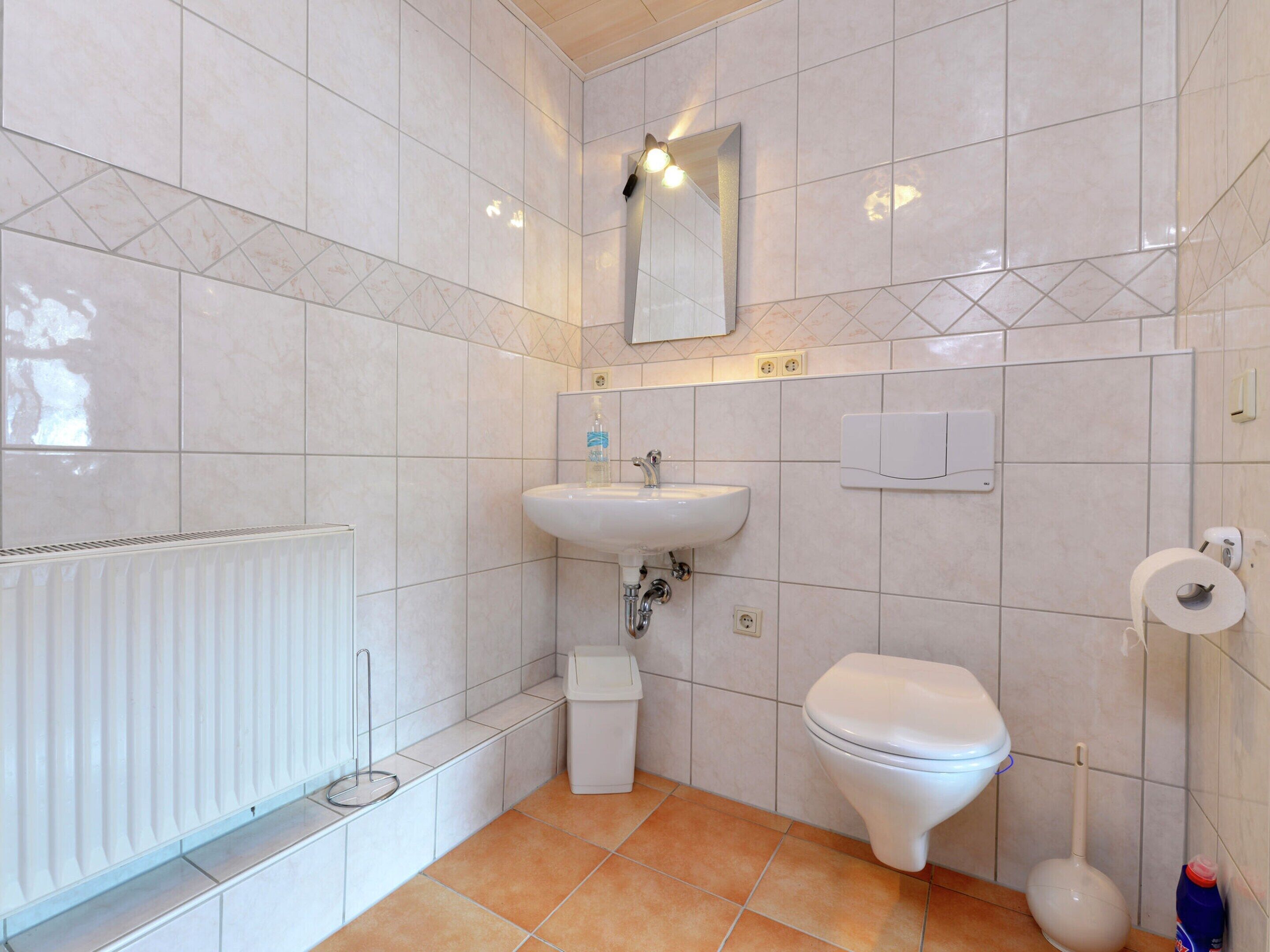 Een badkamer met een witte wastafel, toilet en handdoekradiator.