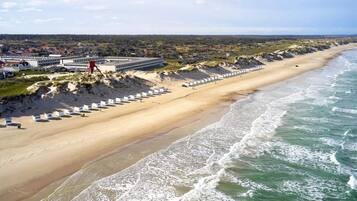 A coastal hotel with a long beachfront, sandy beach, and ocean waves.