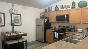A modern kitchen with wooden cabinets, stainless steel appliances, and a dining area with a table and chairs.