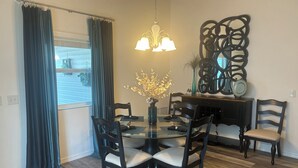 A dining area with a glass table surrounded by chairs, a chandelier, and a decorative mirror.