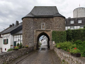 A stone archway leading to a street with traditional buildings, one labeled "Burghof". - Gemutliche Wohnung in Hellenthal (Hellenthal)