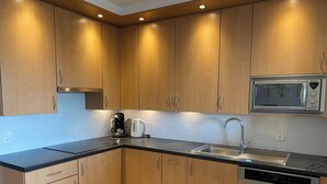 A modern kitchen with wooden cabinets, a stainless steel sink, a microwave, and a coffee maker. - Apartment Nieuwpoort Near Beach & Marina (Nieuwpoort)
