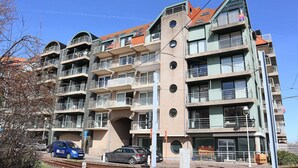 A multi-story building with balconies, a parking area, and a train track. - Apartment Nieuwpoort Near Beach & Marina (Nieuwpoort)