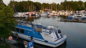 A marina with various boats docked, a blue and white boat in the foreground, and a parking sign nearby. - Holiday Apartment Amsterdam (Plau am See)