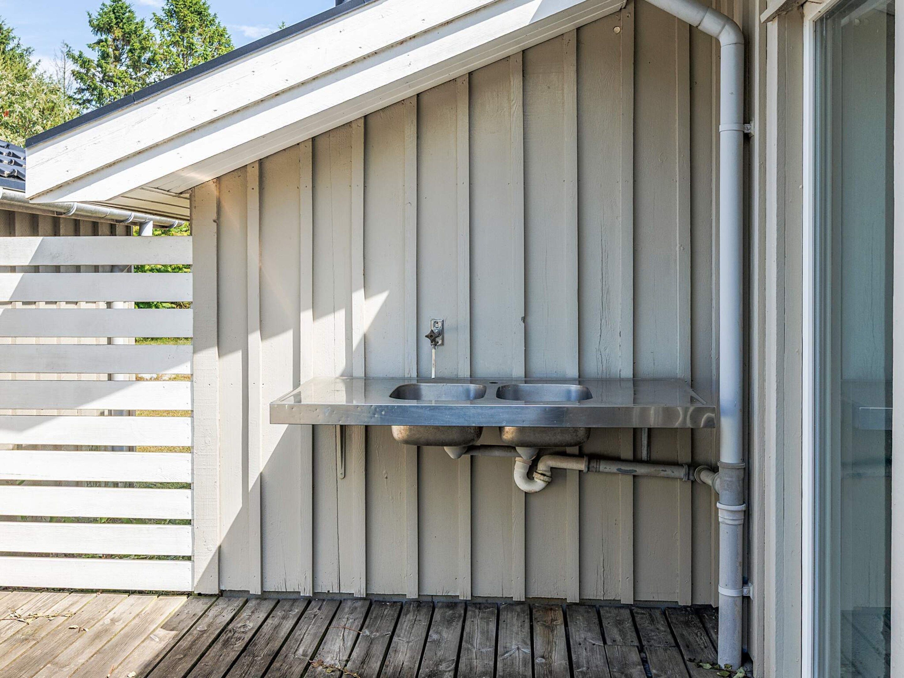 A covered outdoor area with a metal sink and a window.