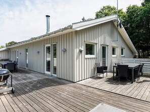 A modern building with a sloped roof, a chimney, and a deck with outdoor furniture. - 12 Person Holiday Home in Rodby (Rodby)