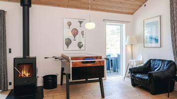 A cozy living room with a wood-burning stove, a sofa, and a dining table.