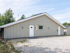 A single-story building with a gabled roof, a door, and a small window.