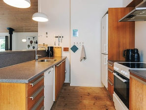 Een kleine keuken met houten kastjes, een roestvrijstalen spoelbak en een ingebouwde oven.