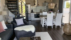 A modern living room with a sofa, coffee table, and a staircase leading to a kitchen. - Beach Apartment Nordstern (Scharbeutz)