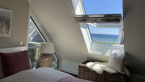 A bedroom with a skylight, a bed, a lamp, and a view of the sea. - Beach Apartment Nordstern (Scharbeutz)