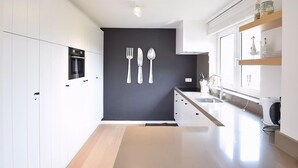 Ett modernt kök med vita skåp, en svart accentvägg och en minimalistisk design.
