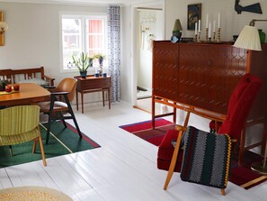 A dining area with a wooden table, chairs, and a red and green patterned rug. - 3 Person Holiday Home in Traslovslage (Träslövsläge)
