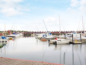 A marina with multiple boats docked, a wooden dock, and red-roofed buildings in the background. - 3 Person Holiday Home in Traslovslage (Träslövsläge)
