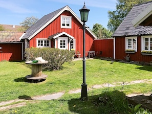 A red wooden house with a white window, a garden with a stone table, and a black lamppost. - 3 Person Holiday Home in Traslovslage (Träslövsläge)