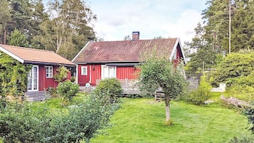 Une grange rouge au toit en pente, entourée d’une pelouse bien entretenue et d’une végétation luxuriante.