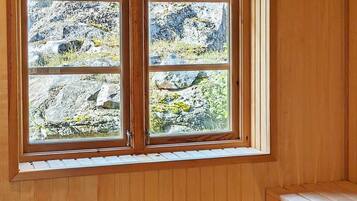 Une fenêtre donnant sur un paysage rocheux et dont l’intérieur est en bois.