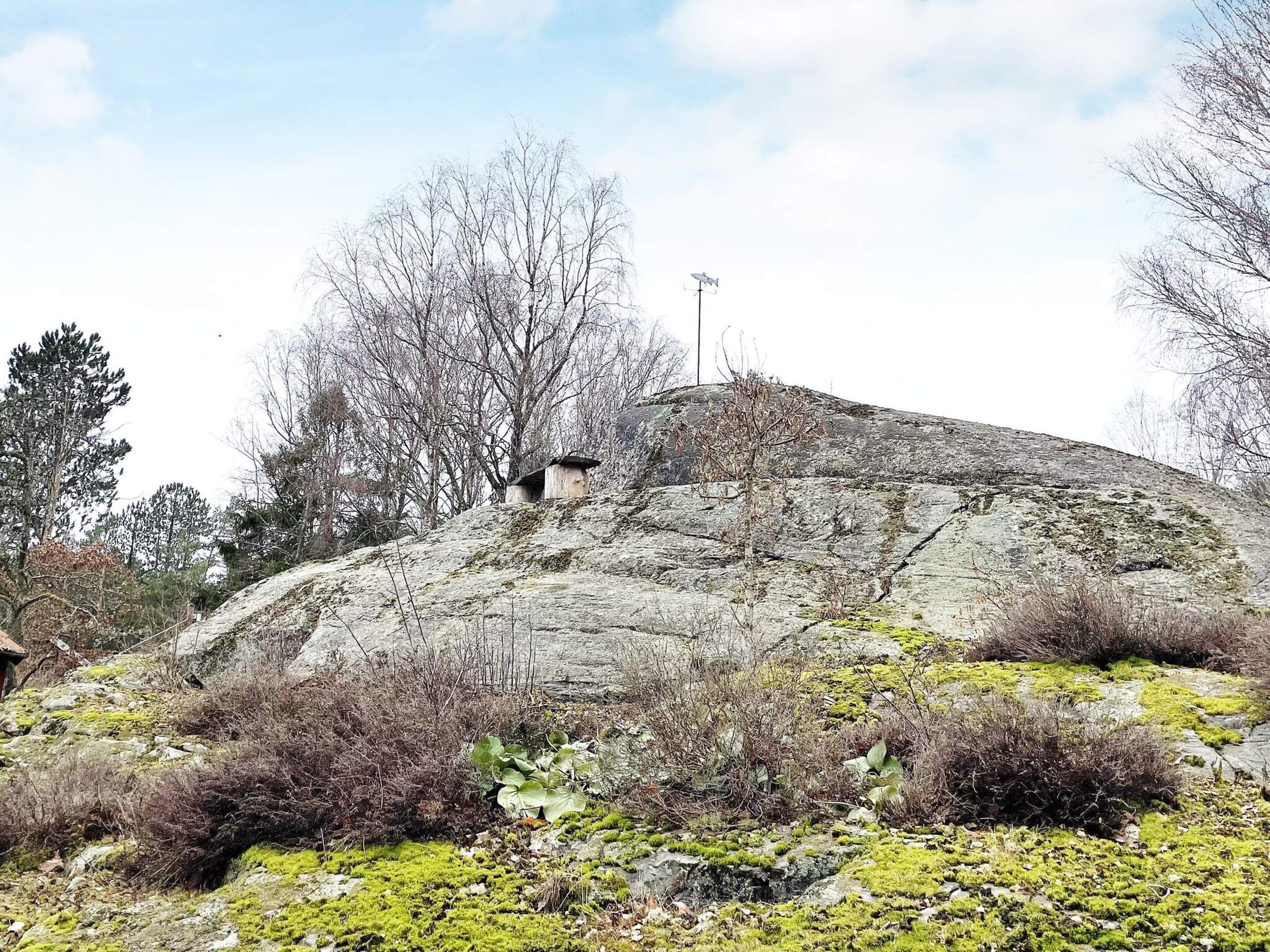 Une colline rocheuse à la végétation clairsemée, surmontée d’une petite construction.
