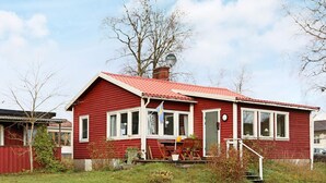 A red wooden house with a red roof, white windows, and a small porch with a table and chairs. - 7 Person Holiday Home in Falkenberg-by Traum (Falkenberg)