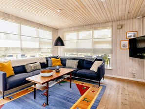 A living room with a dark blue sofa, a wooden coffee table, and a colorful rug. - 4 Star Holiday Home in Hadsund (Hadsund)