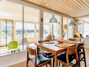 A dining area with a wooden table, chairs, and pendant lights.