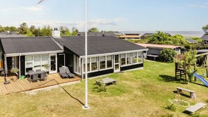 A modern house with a large deck, a flagpole, and a view of the sea. - 4 Star Holiday Home in Hadsund (Hadsund)