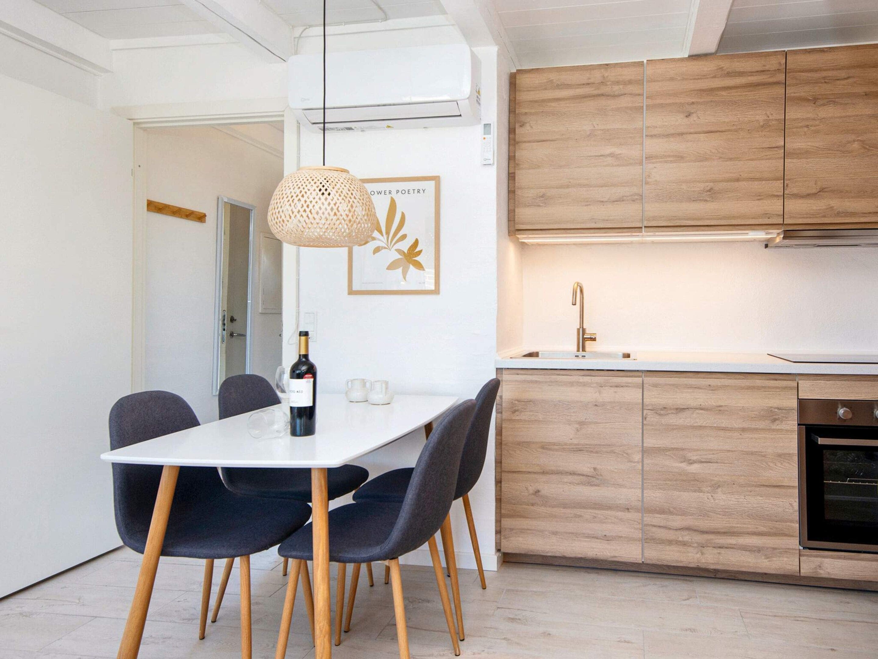 Eine moderne Küche mit Holzschränken, einer weißen Arbeitsplatte und einer hängenden Pendelleuchte.