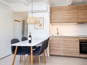 Una cocina moderna con armarios de madera, encimera blanca y una lámpara colgante.