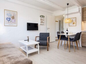 Una sala moderna con un televisor de pantalla plana, un comedor con mesa y sillas, y un sofá.