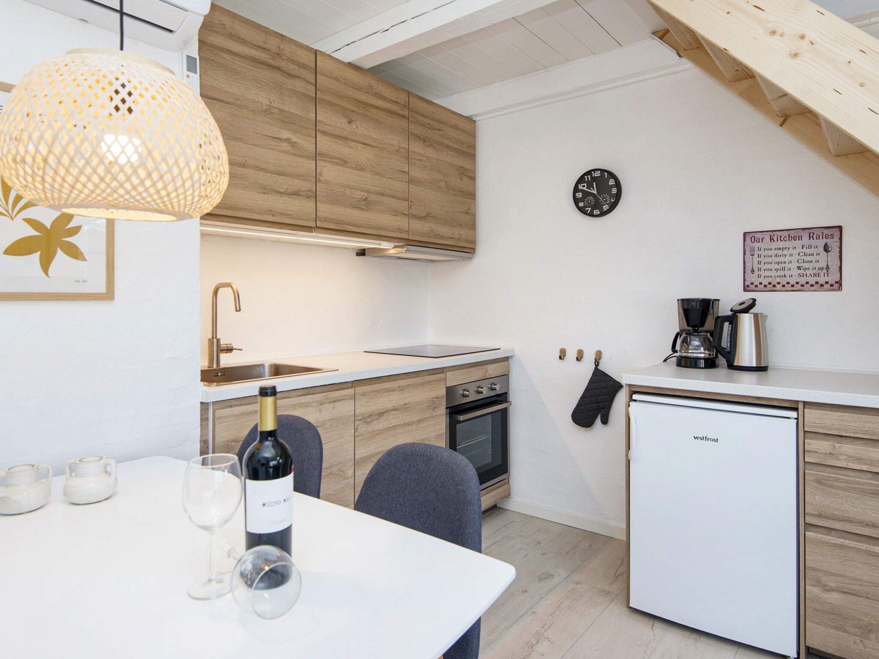 Eine moderne Küche mit Holzausstattung, integriertem Backofen, einer Kaffeemaschine und einem Kühlschrank.