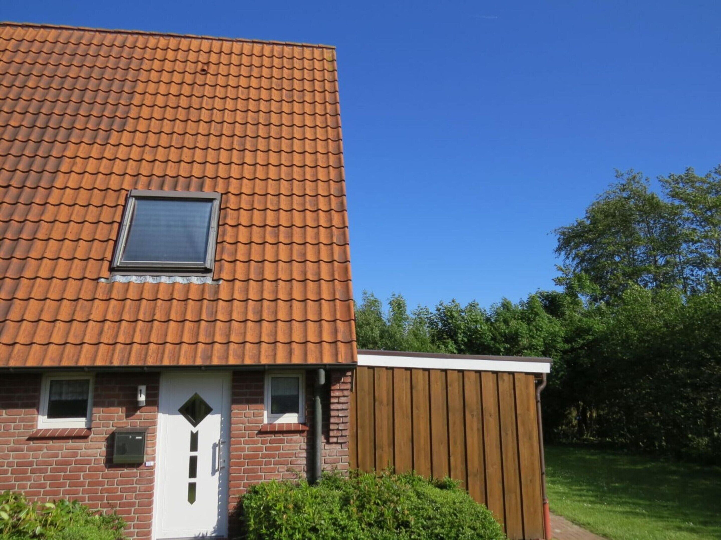 Een herenhuis met een rood pannendak, een klein raam en een witte deur.