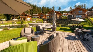 A wooden deck with outdoor furniture, a pool, and a view of wooden cabins. - Beautiful Chalet With Sauna in Wolting (Tamsweg)