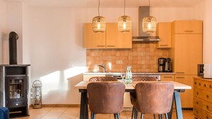 A modern kitchen with wooden cabinets, a central island, and pendant lighting. - Holiday Apartment Coastal Love (Ostseebad Wustrow)