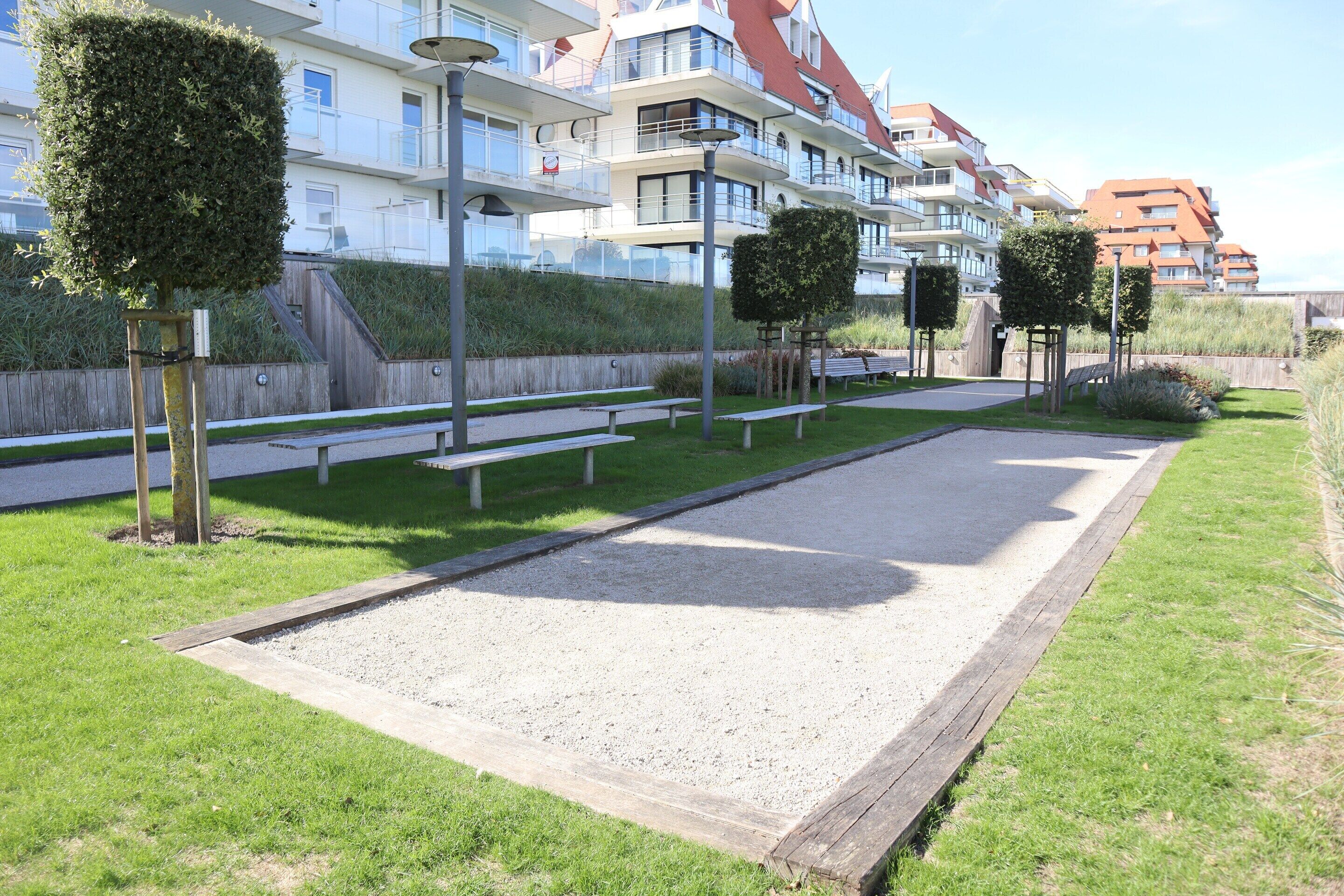 A courtyard with a lawn, benches, and a paved area.