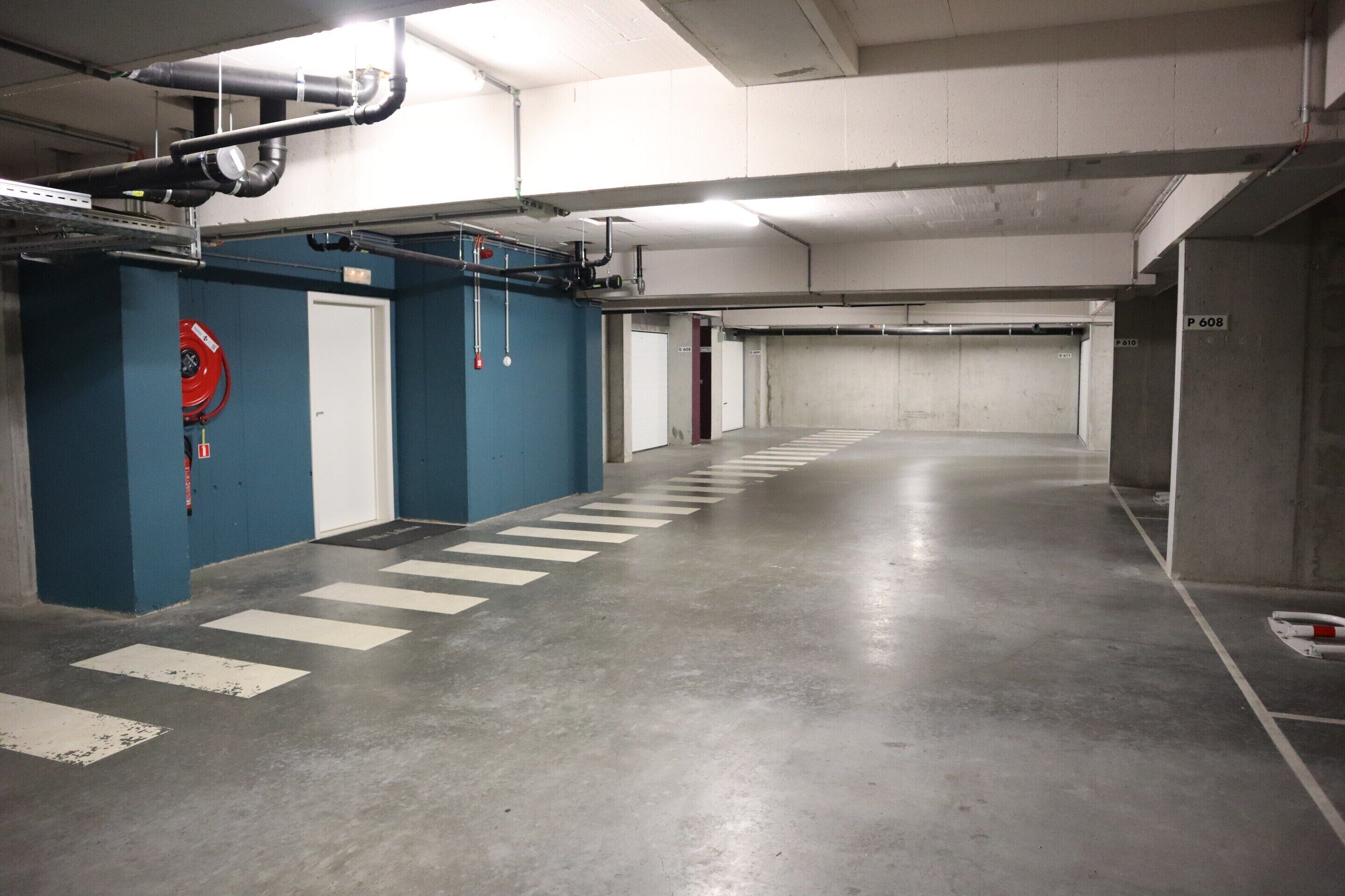 A multi-level parking garage with concrete floors, blue walls, and white doors.