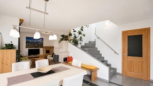A modern living space with a dining area, kitchen, and staircase. - Apartment in Aschau Near Ski Lift Kaltenbach (Aschau Im Zillertal)