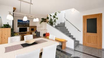 A modern living space with a dining area, kitchen, and staircase.
