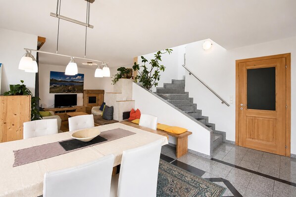 A modern living space with a dining area, kitchen, and staircase. - Apartment in Aschau Near Ski Lift Kaltenbach (Aschau Im Zillertal)