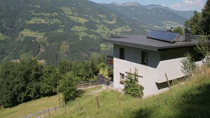 A modern house with solar panels on the roof, surrounded by lush green hills and mountains. - Apartment in Aschau Near Ski Lift Kaltenbach (Aschau Im Zillertal)
