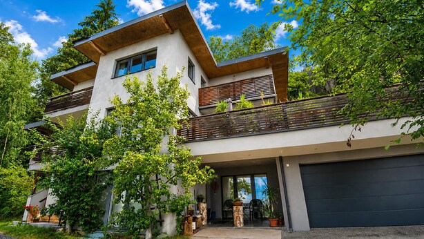 A modern two-story house with a garage, surrounded by lush greenery and trees. - Apartment in Aschau Near Ski Lift Kaltenbach (Aschau Im Zillertal)