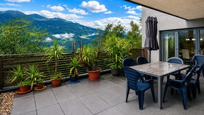 A terrace with a table and chairs, potted plants, and a view of mountains. - Apartment in Aschau Near Ski Lift Kaltenbach (Aschau Im Zillertal)