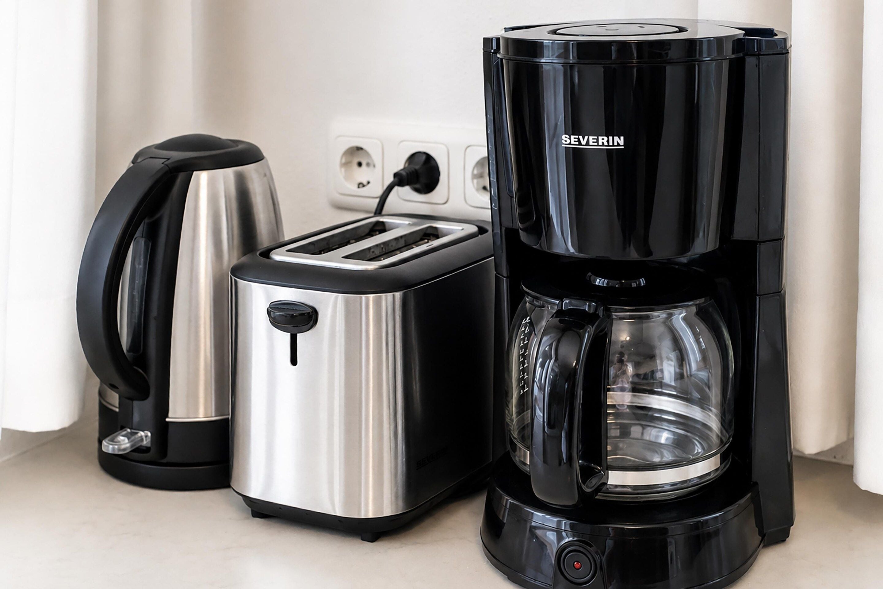 A kitchen with a toaster, a kettle, and a coffee maker.